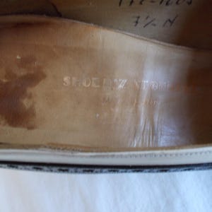 May include: Close-up of the interior of a shoe, showing the insole with the embossed text "SHOEZ STORE" and "Made in Italy". The shoe size is marked as 7 1/2 N. The insole is a light brown color.