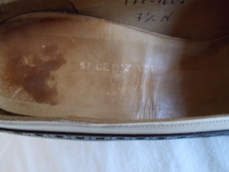May include: Close-up of the interior of a shoe, showing the insole with the embossed text "SHOEZ STORE" and "Made in Italy". The shoe size is marked as 7 1/2 N. The insole is a light brown color.