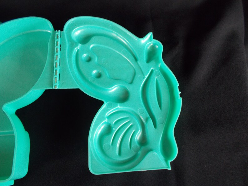 May include: A teal blue plastic mold with multiple compartments, shaped like a butterfly. The mold is open and ready to be used.