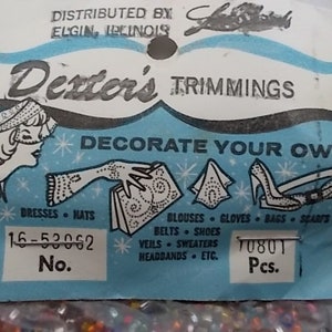 May include: Vintage Dexter's Trimmings label with a light blue and white design. The label features illustrations of dresses, hats, gloves, and shoes. Text includes "Decorate Your Own" and a list of items. The label also has a number and quantity.