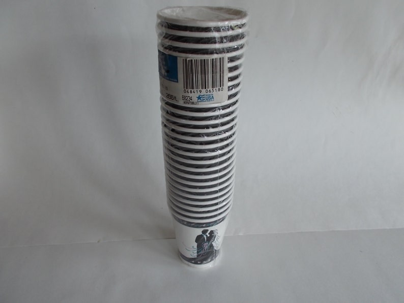 May include: A stack of 50 white paper cups with black stripes and a wedding couple design. The cups are wrapped in plastic and have a barcode label with the text "048419 005180".
