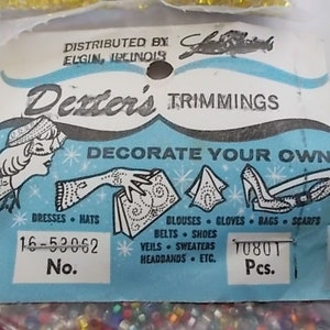 May include: Vintage Dexter's Trimmings package with a light blue and white design. The package features illustrations of dresses, hats, gloves, and shoes. Text includes "DECORATE YOUR OWN" and "16-53062 No."