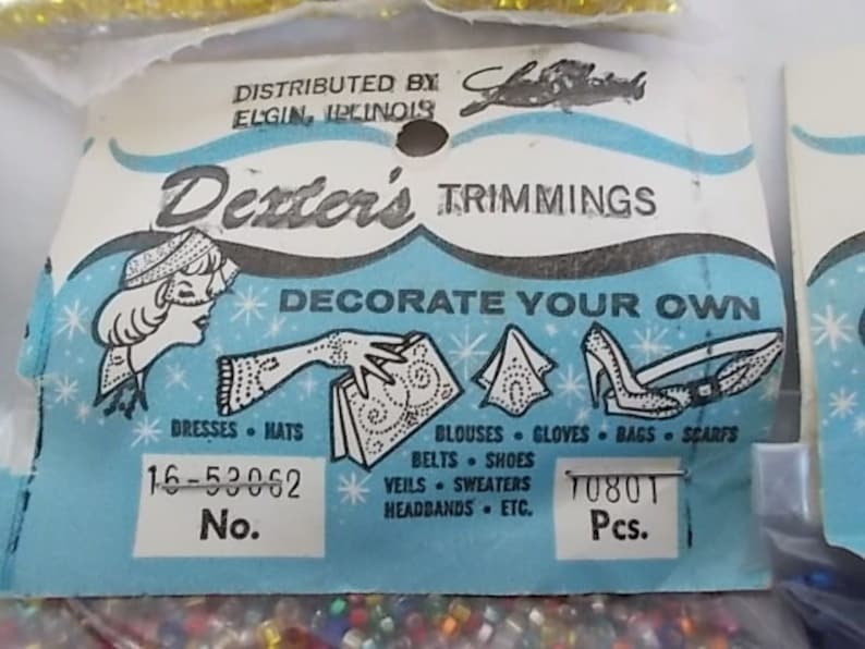 May include: Vintage Dexter's Trimmings package with a light blue and white design. The package features illustrations of dresses, hats, gloves, and shoes. Text includes "DECORATE YOUR OWN" and "16-53062 No."