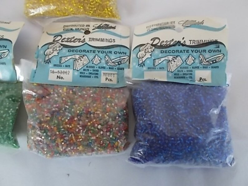 May include: Bags of Dexter's Trimmings, each with a label that reads "Decorate Your Own." The bags contain small, colorful beads. The labels are light blue and white, with illustrations of items to decorate.