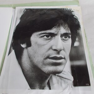 May include: Black and white photograph of a man with dark hair and a serious expression. He is wearing a collared shirt.