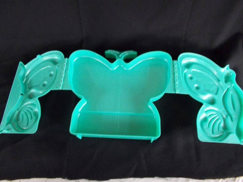 May include: A teal plastic butterfly-shaped box with a hinged lid. The box is divided into three sections.