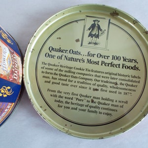 Op de afbeelding: Een vintage Quaker Oats koekjestrommel met een geel deksel en een zwart-witte illustratie van een man die een rol papier vasthoudt. Het deksel heeft de tekst "Quaker Oats...for Over 100 Years, One of Nature's Most Perfect Foods."