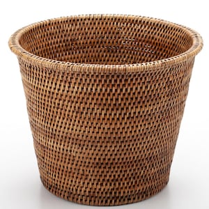 Peut inclure: Une corbeille à papier en osier tressé avec un dessus rond et un corps légèrement conique. Le panier est fait d'osier de couleur naturelle et a une surface texturée. La corbeille est conçue pour une utilisation en intérieur.