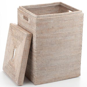 May include: A rectangular, off-white woven laundry hamper with a matching lid. The hamper has a square opening and two handles on the top. The lid is slightly ajar, revealing the interior. The hamper is made of a natural fiber.