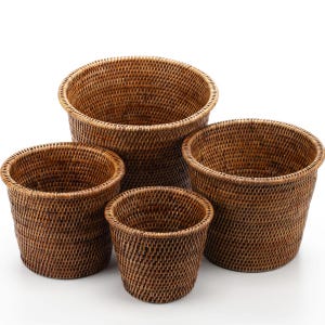 May include: Four woven rattan baskets in different sizes. The baskets are a warm brown colour and have a round shape. The largest basket is approximately 30 cm in diameter, while the smallest is about 15 cm.