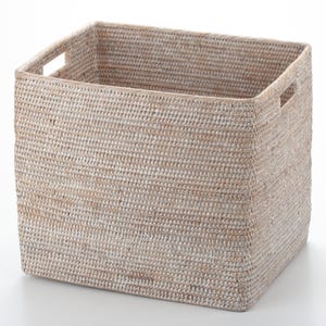 Puede incluir: Una cesta de almacenamiento cuadrada y tejida, de color claro y neutro. La cesta tiene forma rectangular con dos asas integradas en los laterales. El patrón de tejido es visible, y la cesta parece robusta y funcional para la organización del hogar.