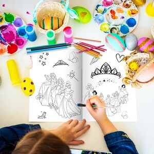 May include: A young person colors a princess-themed coloring book with markers and crayons. The book features illustrations of princesses in gowns and crowns. The book is open to a page with a scene of princesses in a garden.
