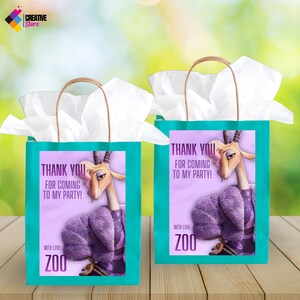 May include: Two teal gift bags with brown handles, each featuring a cartoon gazelle and the text "THANK YOU FOR COMING TO MY PARTY!" and "WITH LOVE: ZOO" on a lavender background. White tissue paper is visible.