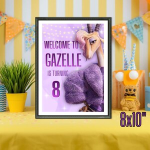 May include: Framed print featuring a cartoon gazelle with the text "Welcome to Gazelle is turning 8." The print is 8x10 inches. The gazelle is wearing a purple coat. The background is light purple with string lights.