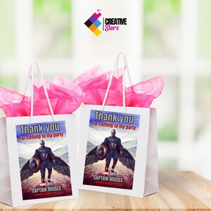 May include: Two white gift bags with pink tissue paper inside. The bags have a printed label with a superhero character, Captain Moises, and the text "Thank you for coming to my party".