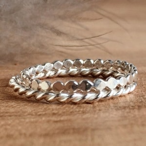 May include: Two silver rings, one with a twisted design and the other with a row of small, round beads.