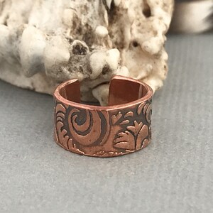 May include: A copper ring with a floral design. The ring is adjustable and has a hammered finish.