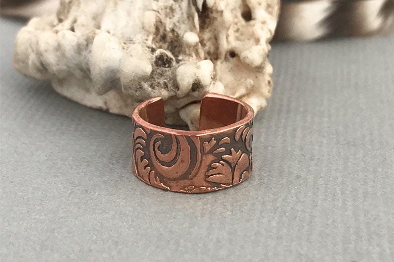 May include: A copper ring with a floral design. The ring is adjustable and has a hammered finish.