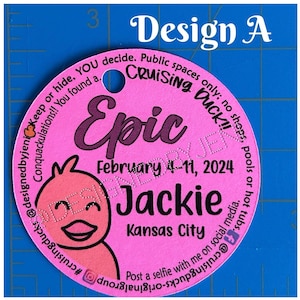 May include: A circular pink tag with a hole at the top, featuring a cartoon duck illustration and black text that reads: Epic, February 4-11, 2024, Jackie, Kansas City, and instructions for cruising ducks, positioned against a blue ruler.