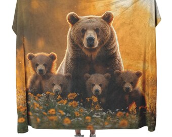 Una osa grizzly y sus crías caminan en un prado resplandeciente de flores silvestres doradas bajo una suave manta polar sherpa naranja con efecto amanecer.