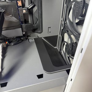 Könnte beinhalten: Innenansicht eines Computergehäuses, das Komponenten zeigt. Das Gehäuse ist überwiegend grau und weiß, mit schwarzen Akzenten. Sichtbar sind Lüfter, Verkabelung und eine Grafikkarte. Das Design deutet auf einen Fokus auf effiziente Kühlung und Komponentenorganisation hin.