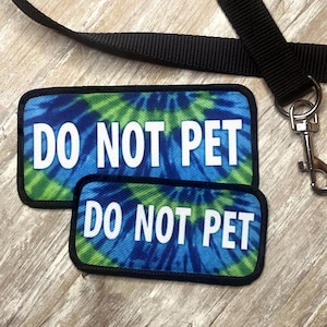 May include: Two blue and green tie-dye fabric patches with black stitching and white text that reads "DO NOT PET".