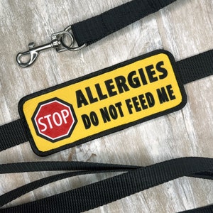 May include: Yellow and black dog leash with a warning sign that reads "ALLERGIES DO NOT FEED ME" and a red stop sign.