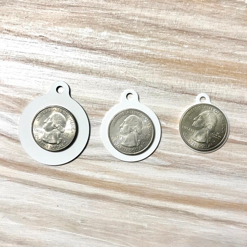 May include: Three silver US quarter dollar coins on white round labels. The coins feature the profile of George Washington and the words "United States of America", "Liberty", and "Quarter Dollar".