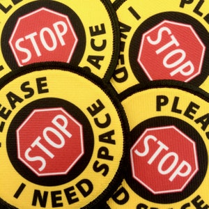 May include: Five yellow and black round fabric patches with the text "I need space" and a red stop sign with the word "STOP" in white.