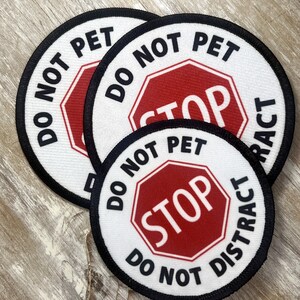May include: Three round white patches with black borders and red stop signs. The text on the patches reads "Do Not Pet, Stop, Do Not Distract".