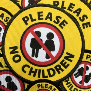 May include: Yellow and black round patch with the text "PLEASE NO CHILDREN" in a circle. A red circle with a diagonal red line through it shows a black stick figure of a boy and girl.