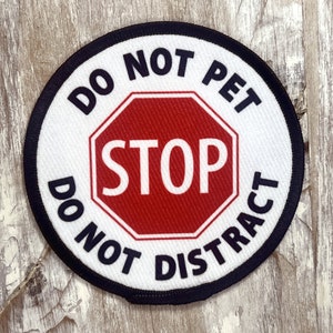 May include: A white round patch with black text that reads "Do Not Pet Do Not Distract" and a red stop sign in the center with white text that reads "STOP".