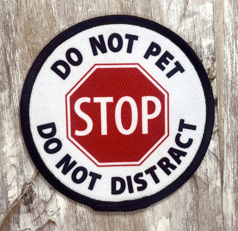 May include: A white round patch with black text that reads "Do Not Pet Do Not Distract" and a red stop sign in the center with white text that reads "STOP".
