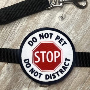 May include: A white round patch with black text that reads "Do Not Pet Do Not Distract" and a red stop sign with white text that reads "STOP" in the center.