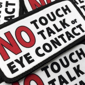May include: White patch with black text that reads "NO TOUCH TALK or EYE CONTACT" in all caps. The word "NO" is in red.