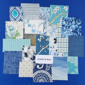 May include: A collection of fabric swatches in various shades of blue, featuring floral, geometric, and abstract patterns. The swatches are arranged in a collage on a blue background. The text "Shades of Blue" is printed on a white label.