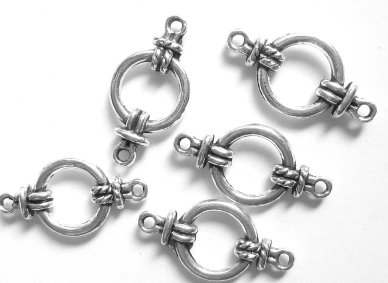 May include: Five silver-toned metal clasps with a decorative rope design. Each clasp has a circular ring and two loops for attaching to jewelry or other crafts.