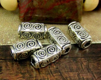 Peut inclure: Cinq perles en métal argenté avec un motif en spirale. Les perles sont de forme rectangulaire et ont un trou au centre.
