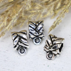 May include: Three silver metal bead caps with a woven design. The caps have a small loop at the bottom.