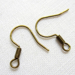 May include: Two antique brass-colored earring hooks. Each hook features a curved design with a coiled wire detail near the bottom and a small loop. The hooks are designed for jewelry making and crafting.