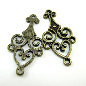 May include: Two antique gold metal filigree charms with intricate swirl designs. The charms have a textured finish and are perfect for adding a vintage touch to jewelry or crafts.