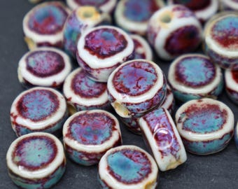 May include: A collection of round ceramic beads with a white glaze and a red and blue marbled pattern. The beads have a hole in the center for stringing.