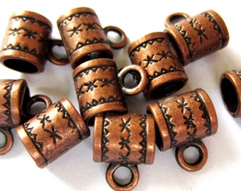 May include: A collection of copper-toned metal cord ends featuring a cylindrical shape with a small attached loop. Each piece displays a textured surface with a repeating pattern of etched zig-zag lines and small star-like markings in dark brown.