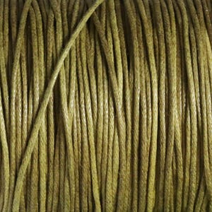 May include: Close-up of a spool of olive green waxed cotton cord. The cord is tightly wound, showing a textured surface. The color is a muted, earthy tone, suitable for various crafting projects.