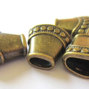 Puede incluir: Cuatro tapones de extremo de metal de color dorado antiguo con un ribete de cuentas decorativas. Los tapones de extremo tienen forma de peque&ntilde;as campanas.