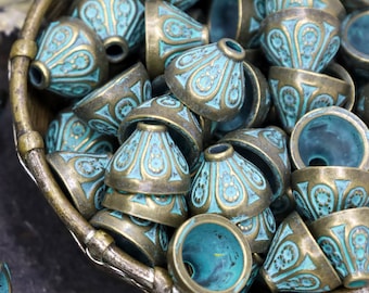May include: A collection of teal blue and gold metal beads with intricate designs. The beads are in a woven basket.