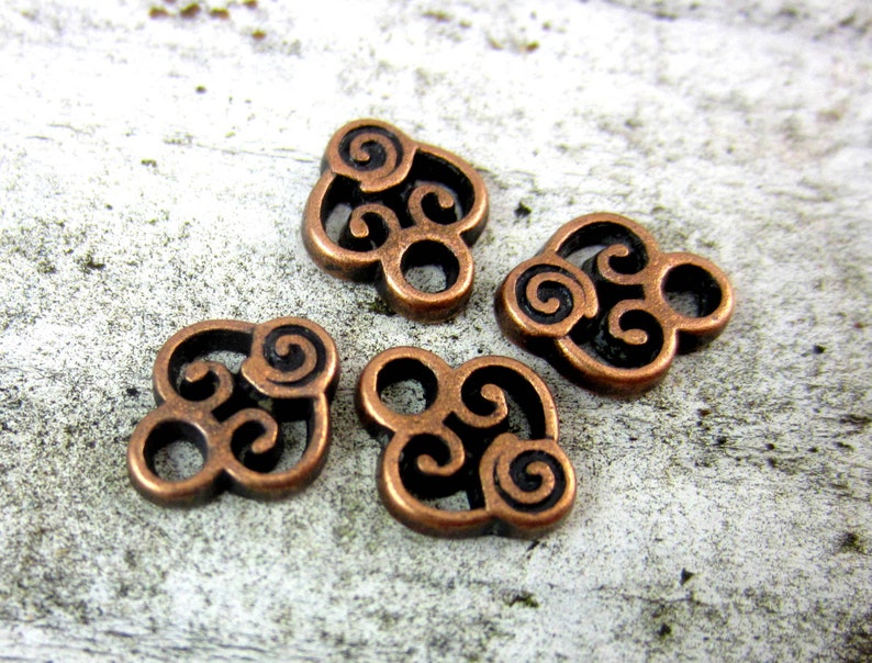 Puede incluir: Cuatro abalorios de metal de color cobre con un dise&ntilde;o de nudo celta en espiral. Cada abalorio tiene un di&aacute;metro de aproximadamente 2,5 cm.