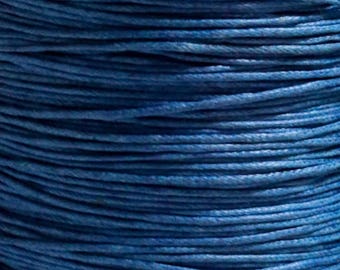 Op de afbeelding: Close-up van een spoel donkerblauw gewaxt koord. Het strak gewikkelde koord heeft een textuur, met zichtbare afzonderlijke strengen. Dit koord is geschikt voor diverse knutsel- en sieradenprojecten.