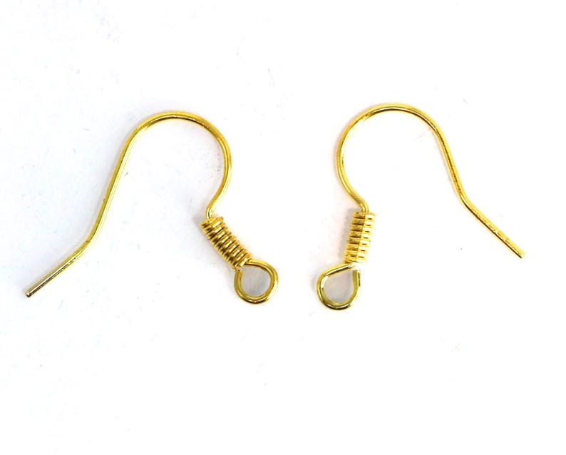 May include: Two gold-colored earring hooks on a white background. Each hook has a curved wire design with a coiled spring detail and a small loop at the bottom. The hooks are designed for jewelry making.