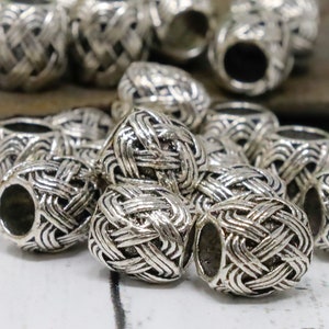 May include: Silver metal beads with a woven design. The beads are round and have a hole in the center.